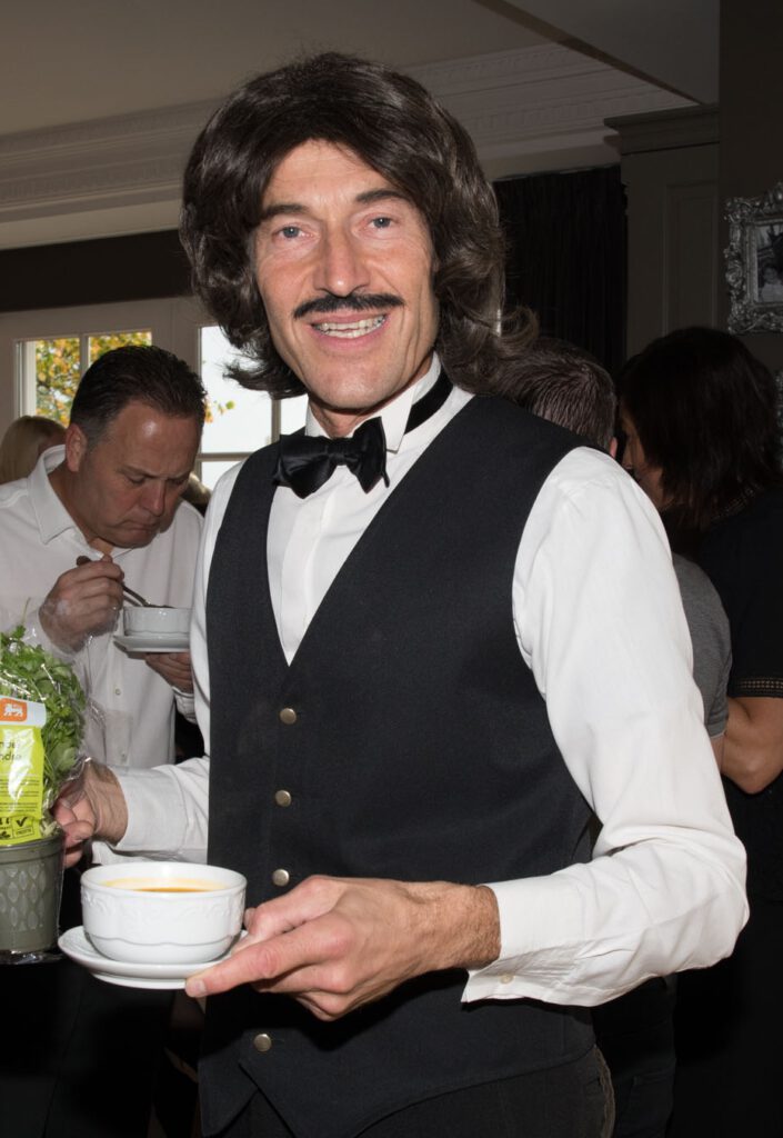 Volijke ober met kopje koffie op feest.