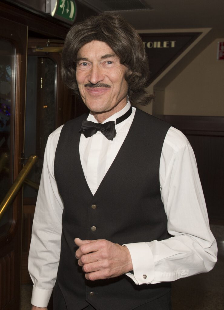 Typetje ober kijkt lachend in de camera.