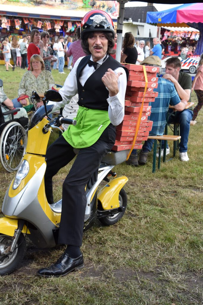 Komisch typetje pizzakoerier van Free Fantasy op festival. Straattheater met veel interactie met het publiek.
