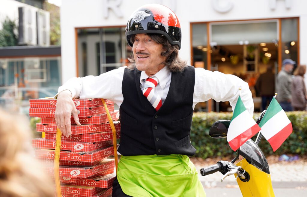 Straattheater typetje pizzakoerier van Free Fantasy. Rijdt vrolijk rond op zijn scootertje, improviseert en reageert op de mensen.