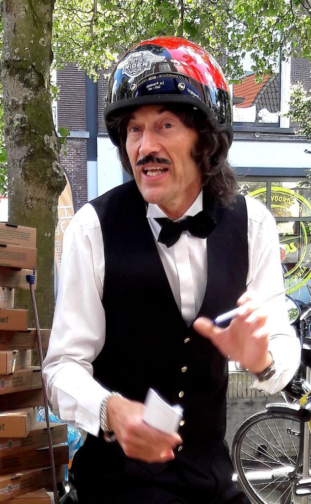 Typetje pizzakoerier neemt bestelling op. Interactieve en komische act, mobiel. Entertainer op straat, straattheater.