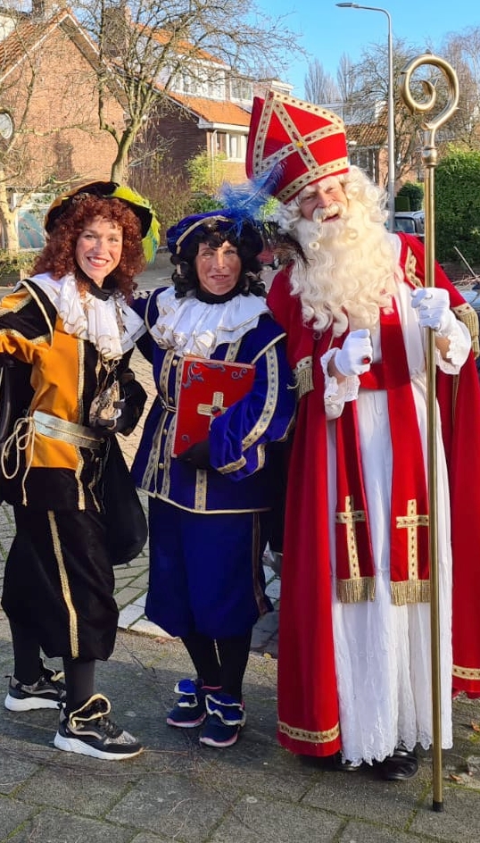 Sinterklaas en pieten poseren buiten en een straat.