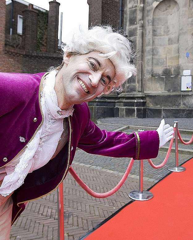 Lachende lakei bij rode loper.