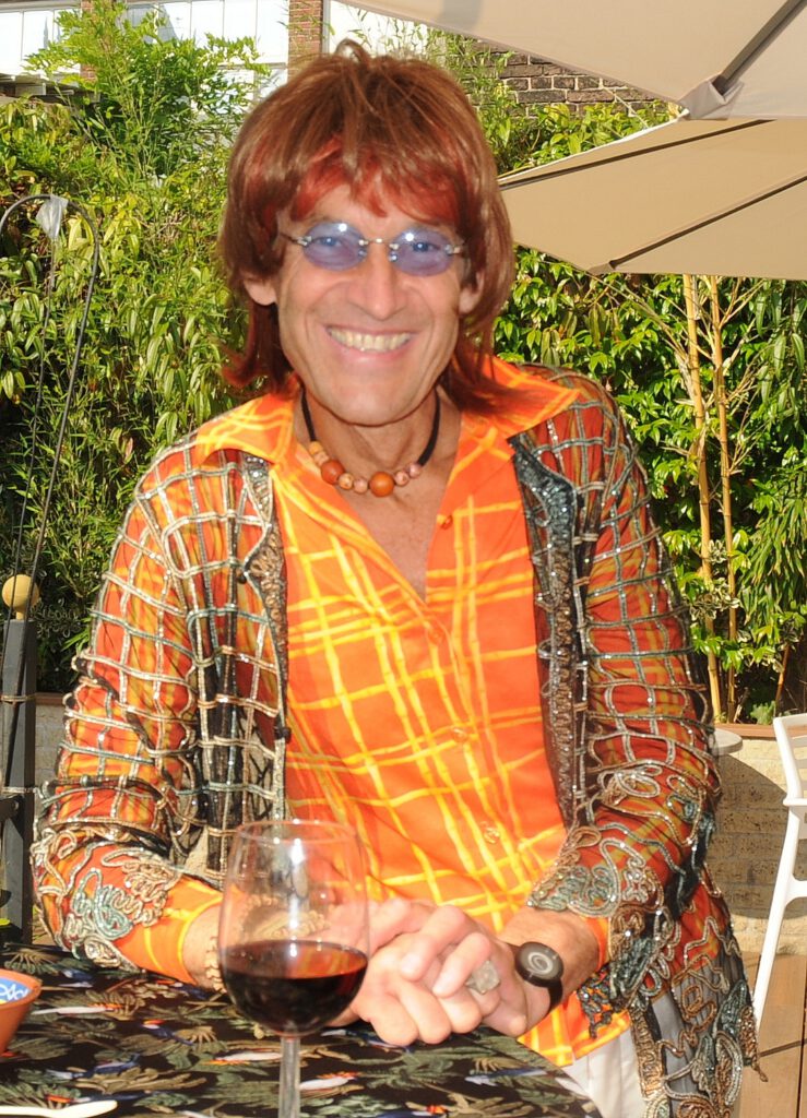 Typetje hippie staat lachend aan een statafel.