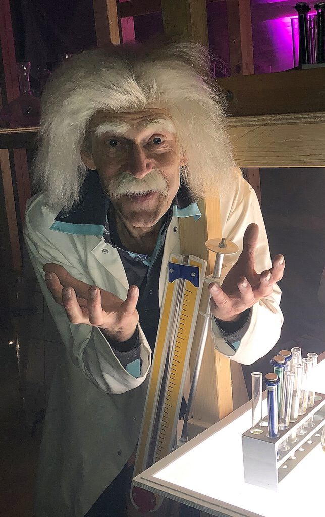 Typetje professor kijkt enthousiast in de camera.