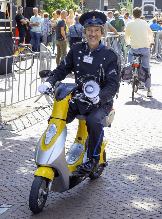 Typetje Brigadier Bob komt op zijn scootertje aanrijden tijdens evenement.