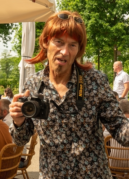 Typetje fotograaf entertaint en maakt foto's tijdens een bedrijfsfeest.